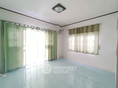 Spacious empty room with large windows and green curtains, perfect for customization.