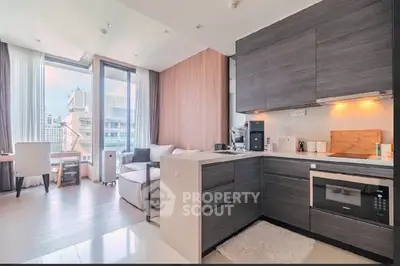 Modern open-layout kitchen with sleek cabinetry and cozy living area, featuring large windows and natural light.