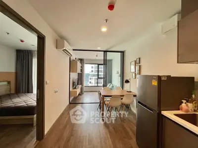 Modern open-plan apartment with stylish kitchen and cozy living area, featuring a view of the bedroom.