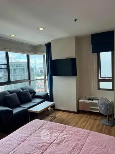 Modern living room with city view, featuring a cozy sofa and wall-mounted TV.