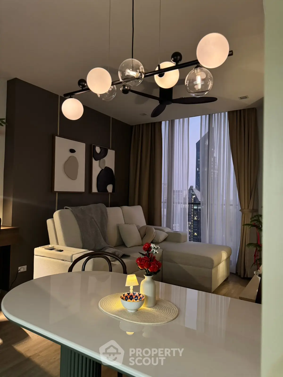 Modern living room with stylish lighting and city view, featuring a cozy sofa and elegant decor.