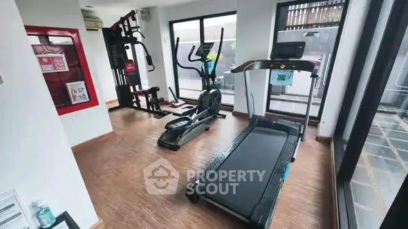 Modern gym with treadmill and exercise equipment in bright, spacious room.
