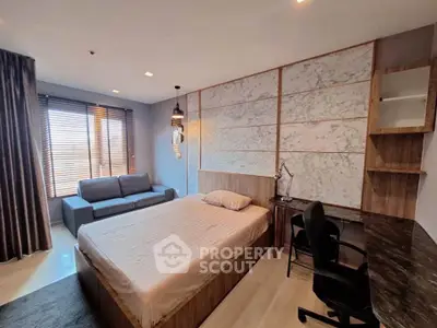 Modern bedroom with stylish decor, featuring a cozy bed, sofa, and work desk near a large window.