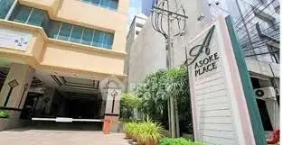 Modern building entrance with Asoke Place sign and lush greenery.