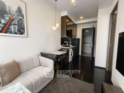 Modern living room with cozy sofa and compact kitchen featuring washing machine.