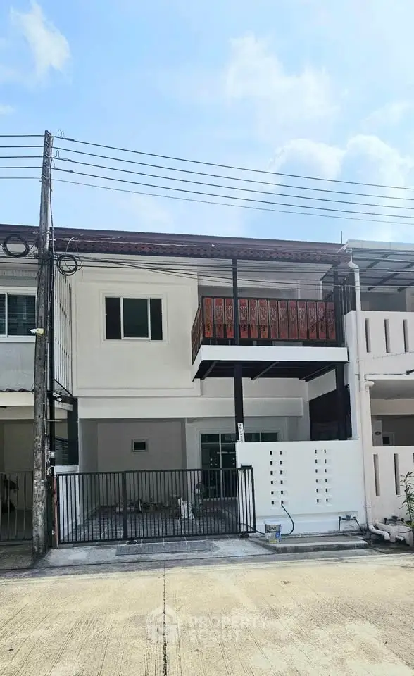 Charming two-story townhouse with balcony and modern facade in a serene neighborhood.