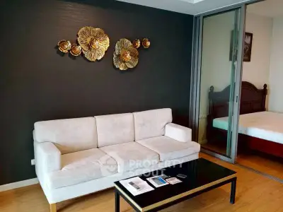 Modern living room with elegant decor and sliding glass doors leading to a cozy bedroom.