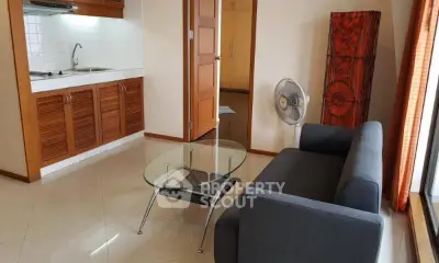 Cozy living room with modern sofa and glass coffee table, adjacent to a compact kitchen.