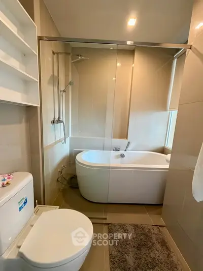 Modern bathroom with glass shower and freestanding bathtub in elegant apartment.