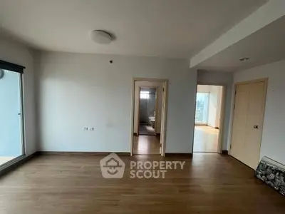 Spacious empty room with wooden flooring and balcony access, ideal for customization.