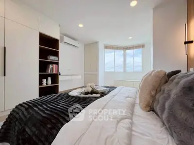 Luxurious bedroom with cozy bedding and ample natural light from large windows.