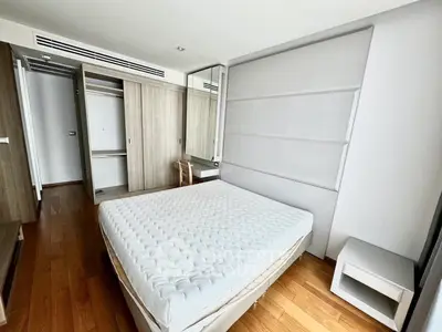 Modern bedroom with wooden flooring and built-in closet in a stylish apartment.