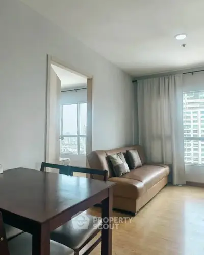 Modern living room with city view, featuring a cozy sofa and dining table, perfect for urban living.