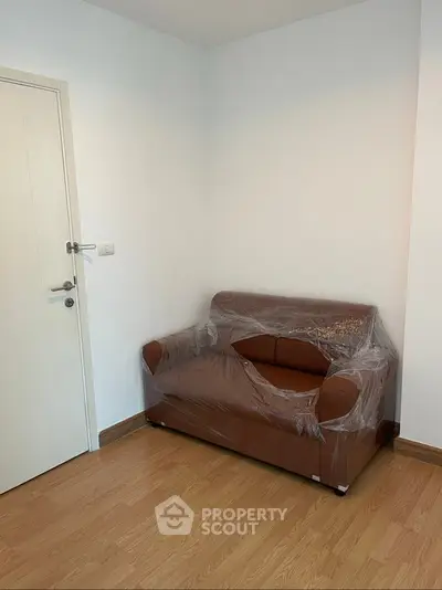 Cozy small living room with a brown leather sofa and wooden flooring, perfect for compact spaces.