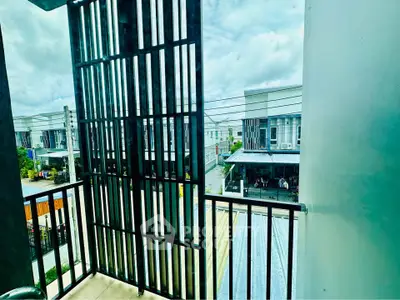 Modern balcony with sleek railing offering a view of contemporary townhouses under a bright sky.