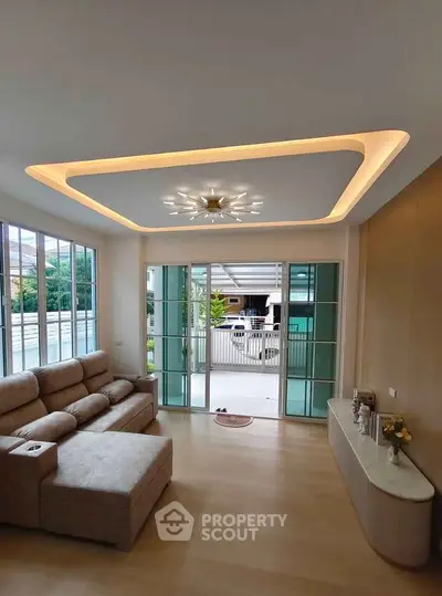 Spacious living room with modern lighting and large windows overlooking a serene outdoor view.