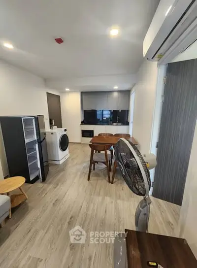 Modern open-plan living area with kitchen, dining table, and appliances.