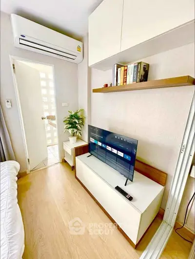 Modern bedroom with sleek TV setup and air conditioning, featuring wooden flooring and stylish shelving.