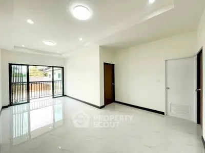 Spacious modern living room with large windows and balcony access, perfect for natural light lovers.
