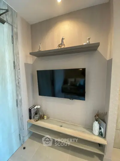 Modern living room corner with mounted TV and decorative shelves in stylish apartment.