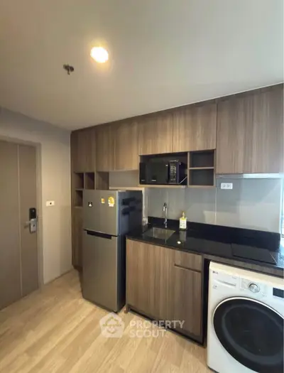 Modern kitchen with sleek cabinetry, stainless steel appliances, and washer-dryer combo in a compact layout.