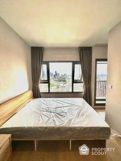 Modern bedroom with city view and large windows in high-rise apartment