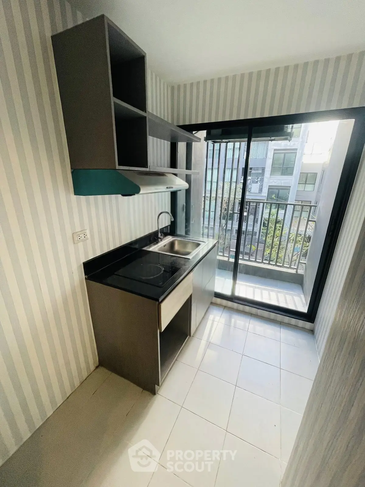 Modern kitchen with sleek cabinetry and large window offering natural light and city view.