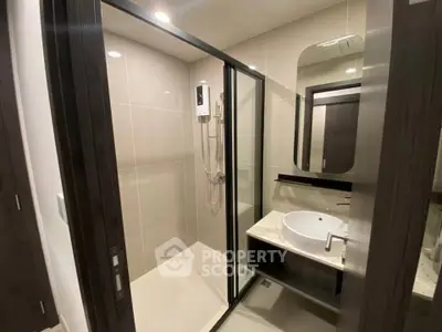 Modern bathroom with glass shower enclosure and sleek vanity in contemporary apartment.