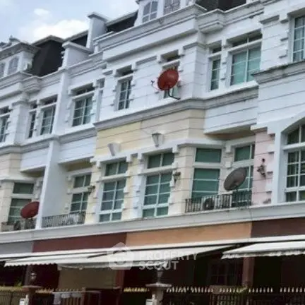 Elegant multi-story building with classic architecture and satellite dishes on balconies.