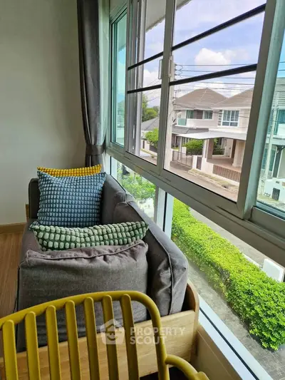 Cozy corner with a view in modern home, featuring plush seating and large windows overlooking suburban street.