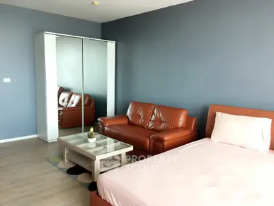 Modern studio apartment with sleek leather sofa and mirrored wardrobe