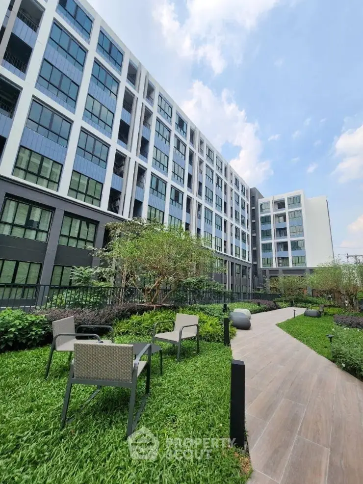 Modern apartment building with lush garden and outdoor seating area