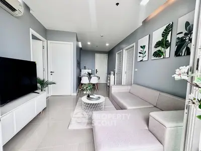 Modern living room with sleek gray sofa, large TV, and stylish decor in a bright apartment.