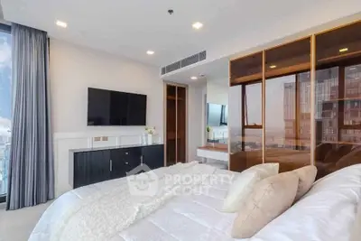 Luxurious bedroom with modern decor and city view, featuring a sleek TV and elegant furnishings.
