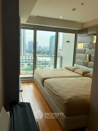 Luxurious bedroom with city view and modern decor in high-rise apartment.