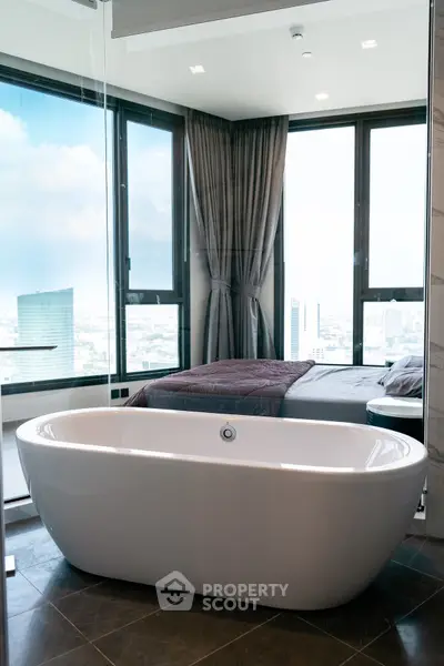 Luxurious bedroom with freestanding bathtub and panoramic city view.