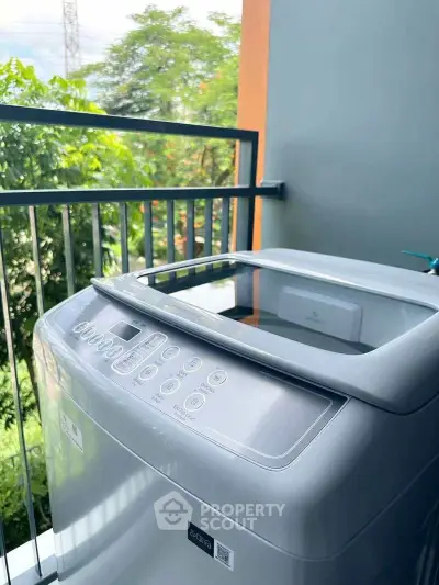 Modern washing machine on a balcony with lush green view