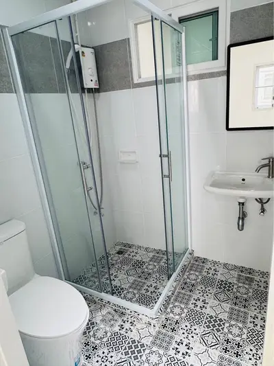Modern bathroom with glass shower enclosure and stylish patterned floor tiles.