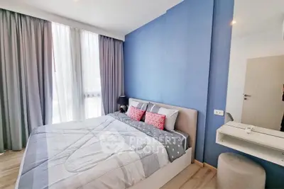 Modern bedroom with blue accent wall and cozy bedding in a stylish apartment.