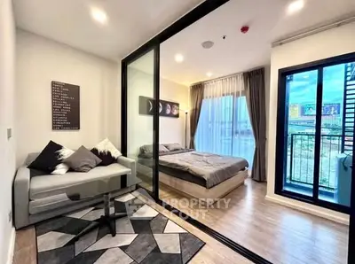 Modern studio apartment with glass partition, cozy living area, and small balcony view.