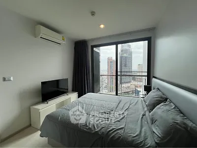 Modern bedroom with city view, featuring sleek furniture and large window for natural light.