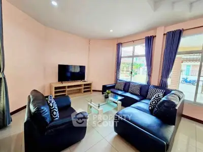 Spacious living room with modern black leather sofas and large windows for natural light.