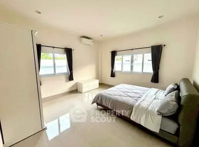 Spacious and bright bedroom with modern furnishings and large windows for natural light.