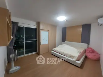 Spacious bedroom with modern decor and city view, featuring a cozy bed and stylish wooden flooring.