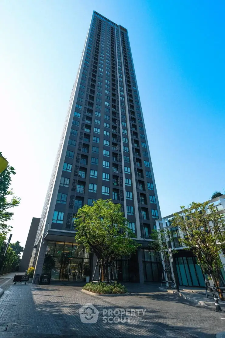 Stunning high-rise building with modern architecture and lush greenery at the entrance.