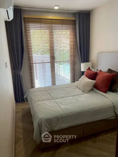 Cozy bedroom with modern decor and large window with blinds, perfect for relaxation.
