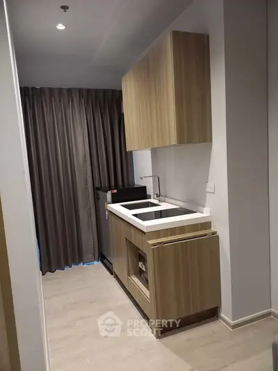 Modern compact kitchen with sleek wooden cabinets and integrated appliances in a stylish apartment.