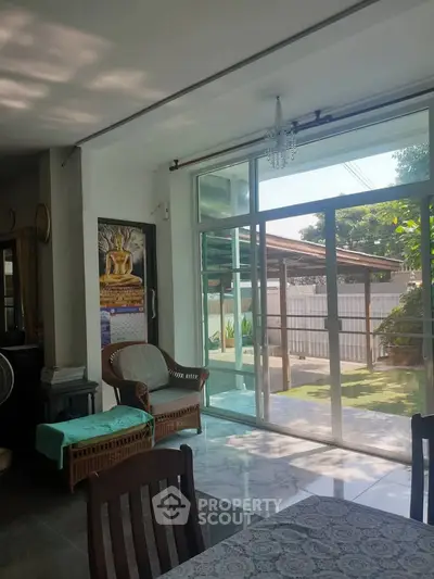 Spacious living room with large windows and garden view, featuring elegant decor and natural light.