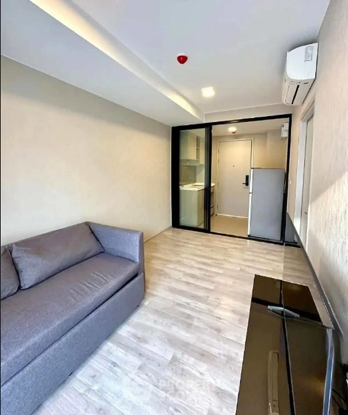 Modern living room with sleek design and glass partition, featuring a cozy sofa and air conditioning.