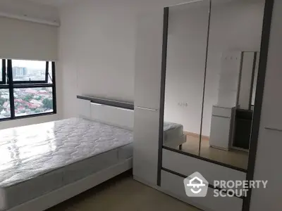 Modern bedroom with large window and mirrored wardrobe offering city views.